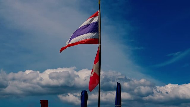 Thailand and Switzerland flags waving at long tail boat docket near popular beach at Phuket, Thailand.