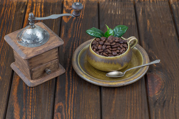 coffee beans in a cup and old manual coffee grinder on a wooden table 
