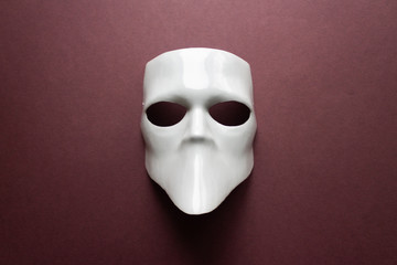 Theatre concept with the white masks on trendy vinous bordeaux, burgundy background. Anonimous, Incognito, Conspiracy concept. Place for text. Flat lay style. Top view