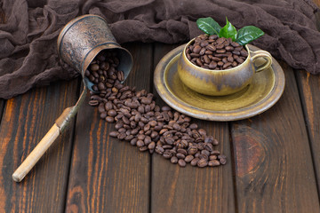 coffee beans in a cup and a coffee maker from it pour coffee beans on a wooden table