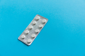 Top view on the pills in the package. White pills on blue background. Medicine, medication,...