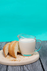 A glass of fermented baked milk and slices of ciabatta bread on a cutting board. On brushed pine boards.