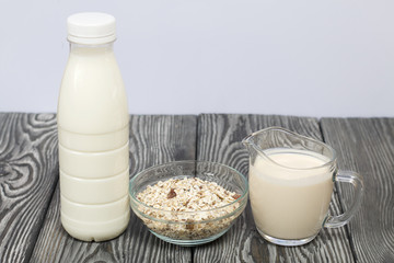 Bottle and glass with milk. Nearby in a muesli container. On brushed pine boards.