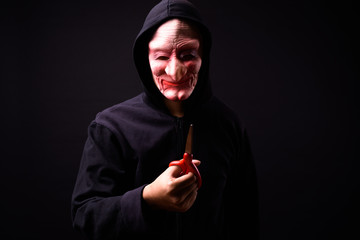 Portrait of young man with hoodie and horror mask holding scissors