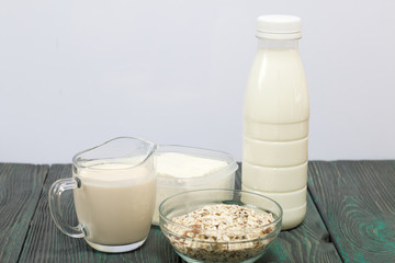 Bottle and glass with milk. Next to granola and soft cheese in a container. On brushed pine boards.