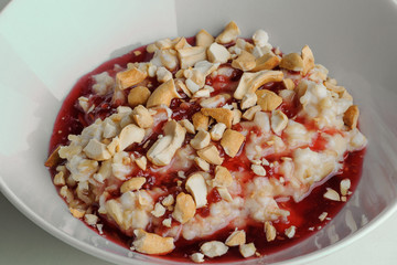Porridge with jam and nuts on a white plate on a white background