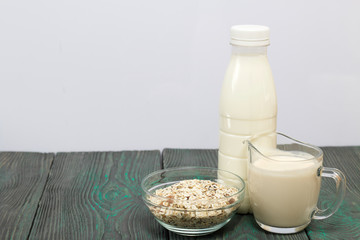 Bottle and glass with milk. Nearby in a muesli container. On brushed pine boards.