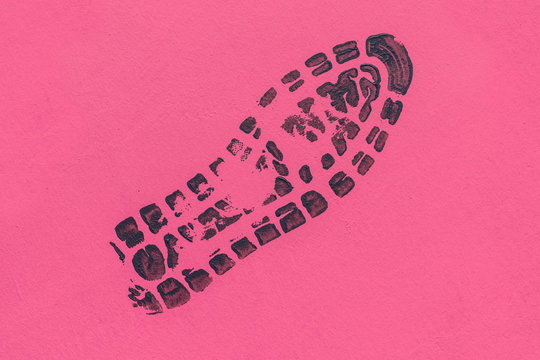 Black paint footprint from shoes on a pink surface.