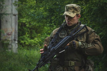 a soldier with a rifle makes his way through the forest