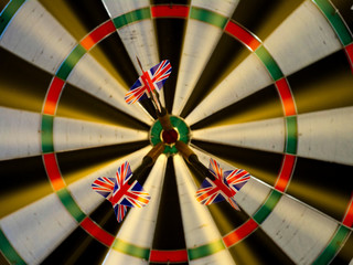 Three darts with UK flags at the center of the target. Success hitting target, goal achievement...