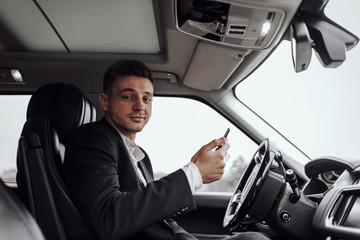 Happy handsome businessman looking at camera in automobile