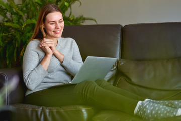 Happy beautiful woman using a laptop computer at sofa in home