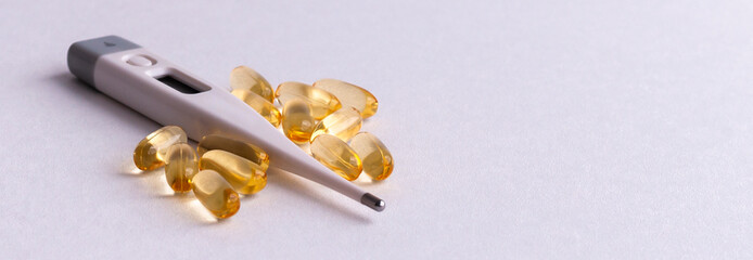Medical digital thermometer with pills and vitamins on a white background