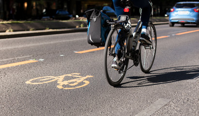 Bicycle lane and car traffic. Cycle lane with orange painted bike on asphalt. Ecological green urban transport.
Fahrradspur und Autoverkehr. Fahrrad Zeichen auf Straße. Ökologischer urbaner Verkehr.