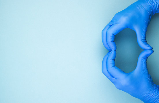 heart sign with hands in blue medical gloves, top view. men's hands represent love on a blue background