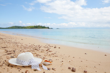 Fototapeta na wymiar Hat on the sandy beach. Beautiful hat on the beach, sun protection concept.
