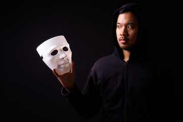 Portrait of young Asian man with hoodie looking at mask