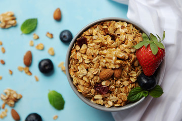 A bowl, a cup of freshly made oatmeal granola stands on a table decorated with berries. Breakfast at home. Cooking granola. Proper nutrition at home