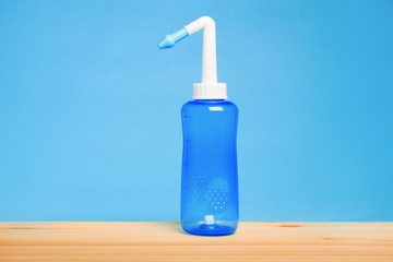 blue water pulse nasal wash bottle on a wooden table, nasal irrigation concept