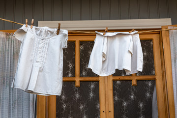 Baby clothes on clothespins are dried on a rope in front of a wooden window. Tbilisi. Georgia