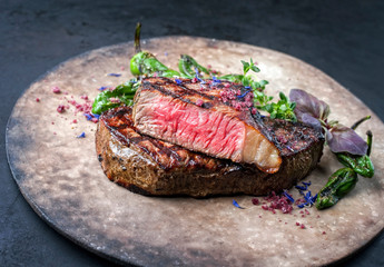Barbecue dry aged wagyu roast beef steak with paprika and herbs as closeup on a rustic modern design plate