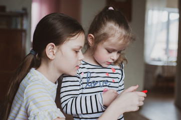 Happy little girls with a smartphone in hands communicate at home with loved ones using modern technology