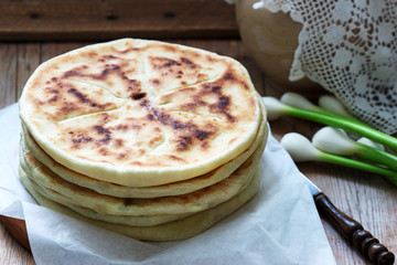 Traditional in different countries pies stuffed with cheese and herbs, fresh garlic and wine on a wooden background.
