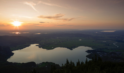 Lake Kochelsee from mountain peak Jochberg during sunset with sun, Staffelsee and Riegsee in the Bavarian Alps, Bavaria Germany.