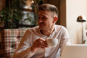 Happy young man holding cup in cafe