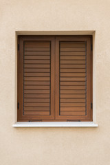 Greek Style windows - wooden vintage window with brown shutters on a beige wall.