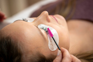 Close-up of the insertion of artificial eyelashes with tweezers in the cosmetic studio, eyelash extension in the cosmetic studio
