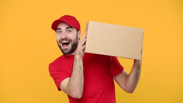 Delivery young guy man in red cap blank t-shirt uniform workwear hold empty cardboard box isolated on yellow background studio Professional male deliveryman employee working as courier Service concept