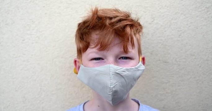 Small red hair aryan blue eyes boy with freckles wearing protective face mask during coronavirus pandemic, detail posing for camera, looking