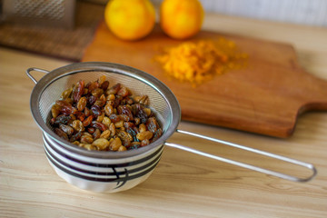 Natural organic dried grapes raisins, rustic still life. Raisins in powdered sugar and orange peel. Prepare the dough. Raisins in a colander