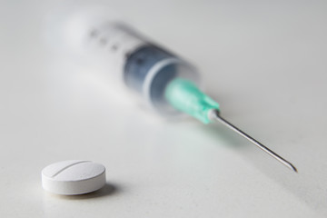 pills together with a medical syringe on a white background