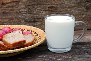A glass of milk on wooden background. Fresh milk. A cup of milk. Healthy food. Rye bread and radish on a wooden tray.