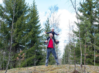 Walk in the woods. Dad and daughter have fun in a forest glade, the girl laughs and sits on the shoulders of a man.