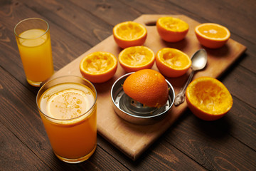 Fresh orange fruits whole and squeezed on a wooden table, cutting board - natural and healthy food. Glass of fruit cocktail.