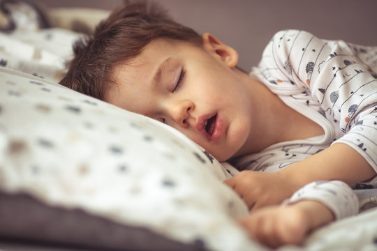 Photo of baby boy sleeping. His favorite napping spot. Adorable kid boy after sleeping in bed. Boy sleeping on bed. Sleepyhead. Little sweet toddler boy sleeping in his bed