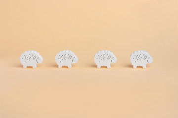 4 figures of a wooden sheep, a lamb on a beige background.