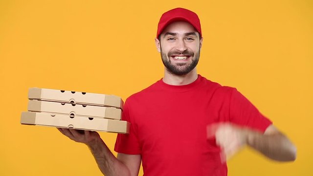 Delivery guy man in red cap t-shirt uniform workwear hold give order empty cardboard pizza boxes takeaway isolated on yellow background studio Professional male employee work courier Service concept