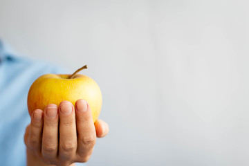 female hand holding  apple on blue background