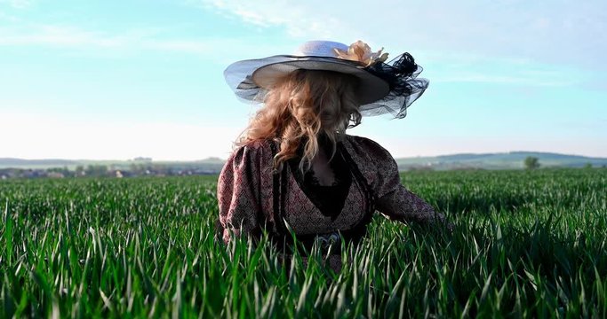 Woman in historic costume with large hat in field opening pandoras box