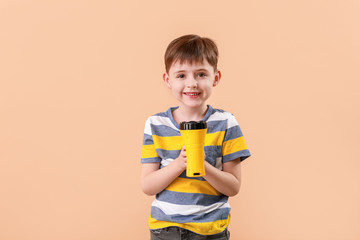 Little boy with flashlight on color background