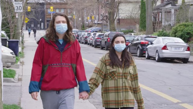 Couple walking on sidewalk with N95 face masks on