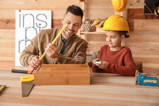 Little son helping his father in carpenter's workshop