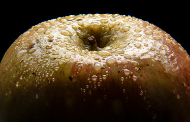 vista de cerca de una manzana roja con gotas de agua sobre el y con fondo negro
