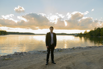 Full body shot of young handsome businessman in front of beautiful scenic shore