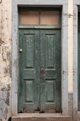 Old green wooden door in damaged stone wall. 