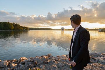 Fototapeta premium Young handsome businessman looking at boat in the river